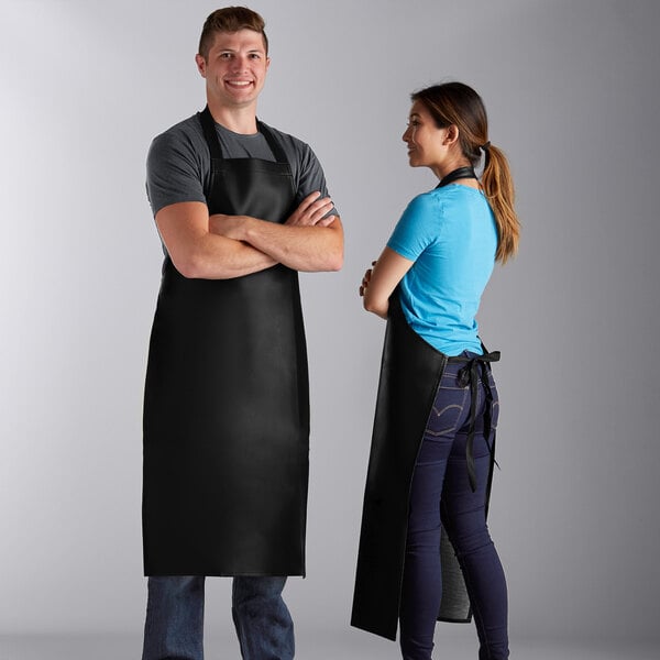 A black heavy weight vinyl dishwasher apron worn by two people, shown from the front and back.