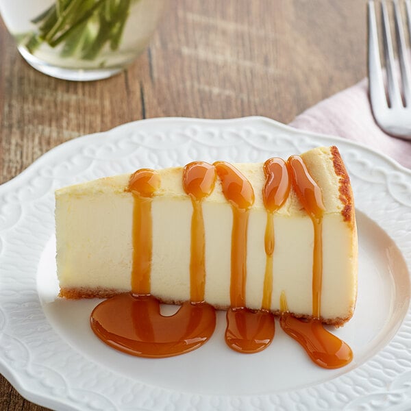 A slice of cheesecake topped with caramel sauce on a white plate.