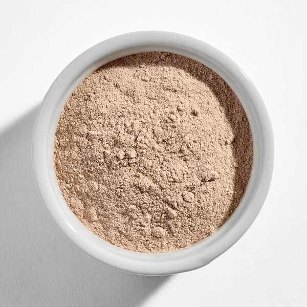 A white bowl filled with light brown chocolate protein powder.