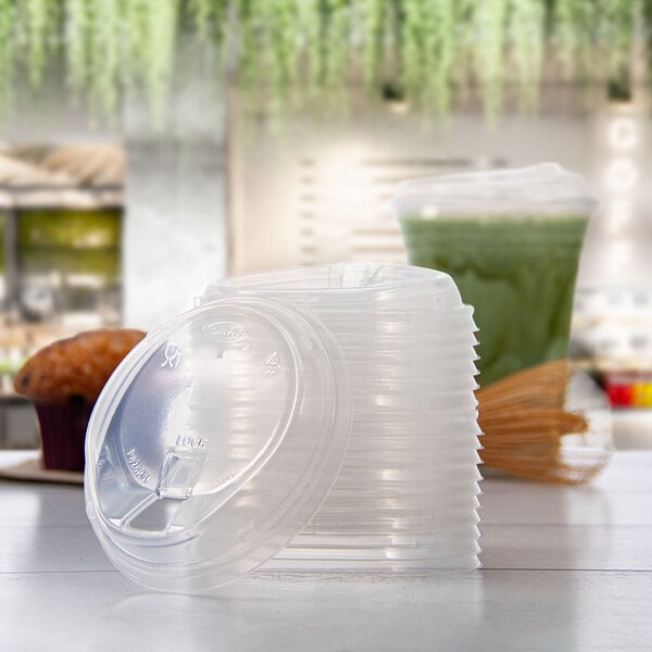 A stack of clear polypropylene reclosable strawless lids for 12-26 oz cups.