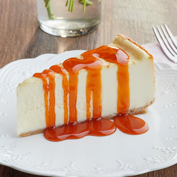 A slice of cheesecake topped with orange pumpkin pie flavored sauce on a white plate.