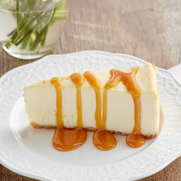 A slice of cheesecake topped with caramel sauce on a white plate.