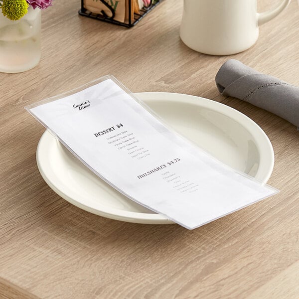 A clear, single-panel, two-view heat-sealed menu cover displayed on a white plate on a wooden table.