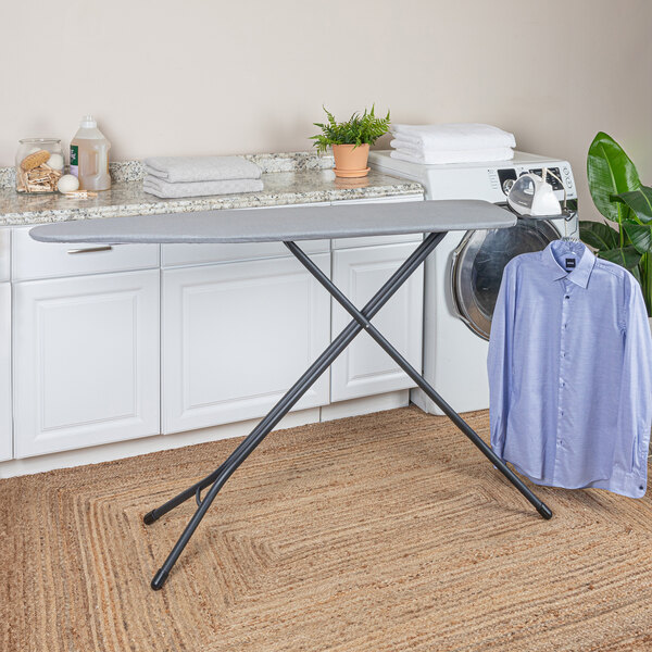 A black steel top ironing board with a cotton cover and an iron rest, set up in a laundry room.