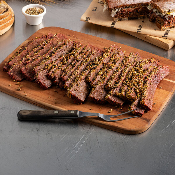 A sliced plant-based vegan steak slab on a wooden cutting board with a serving fork.
