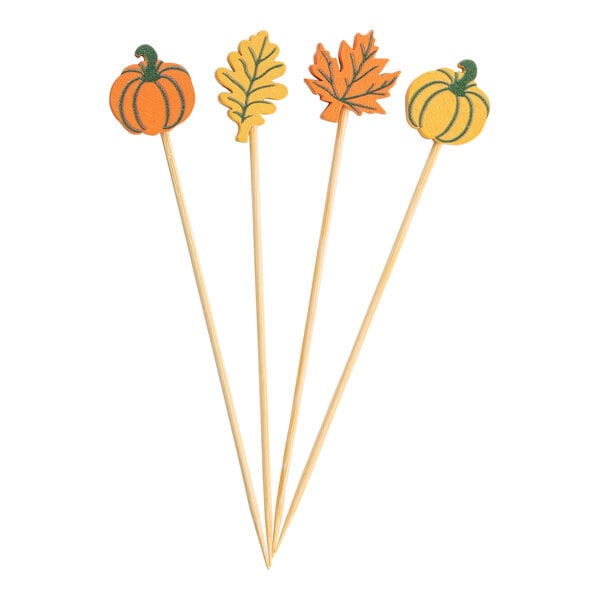 A set of four bamboo food or cocktail picks with fall leaf and pumpkin decorations on top.