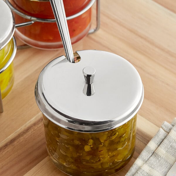 A stainless steel lid with a knob and spoon slot designed for a 7 oz. glass condiment jar.