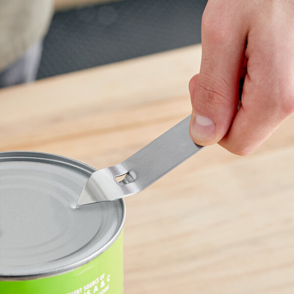 A metal church key can and bottle opener being used to open a can.