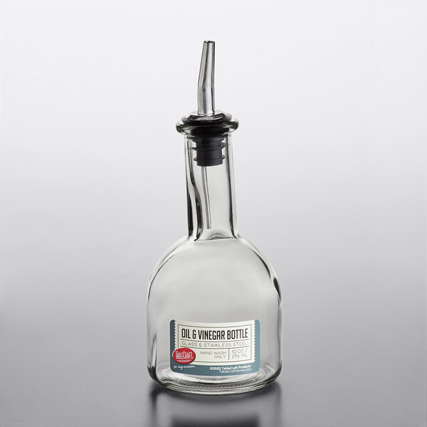 A clear glass oil and vinegar bottle with a stainless steel pourer.