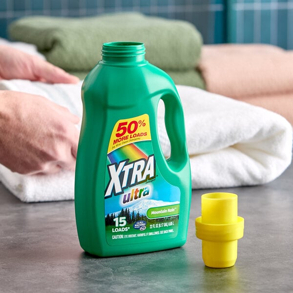 A green bottle of XTRA Ultra Mountain Rain liquid laundry detergent with a yellow cap, labeled for 15 loads.