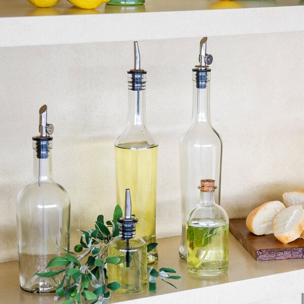 A clear glass oil and vinegar bottle with a weighted stainless steel pourer.