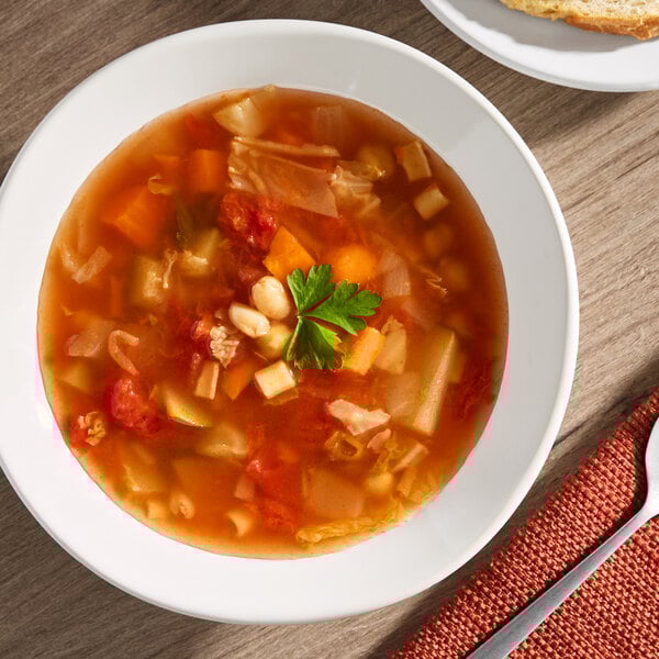 A bowl of minestrone soup with vegetables and beans, garnished with a sprig of parsley.