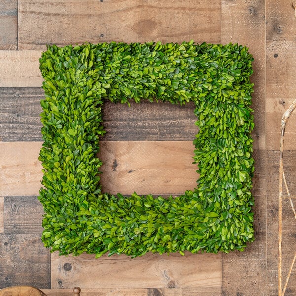 A square wreath made of preserved boxwood leaves.
