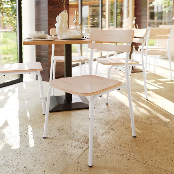 A white metal dining chair with an antique white wooden back and seat.