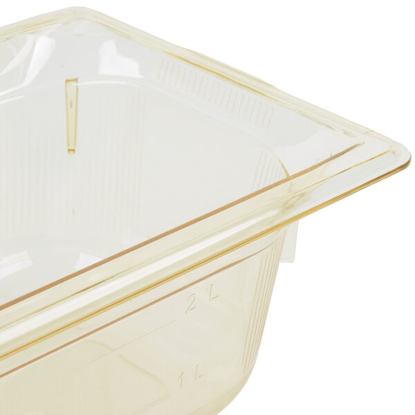 A Vollrath 1/3 size amber plastic food pan with lid on a counter.