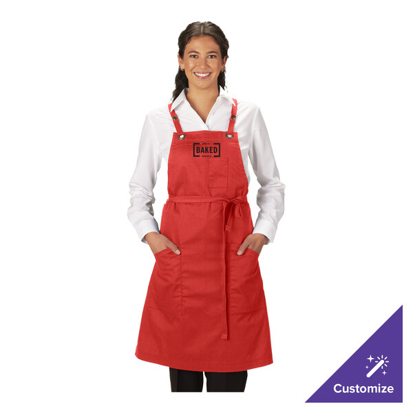 A red customizable poly/cotton cross-back bib apron with three pockets, worn by a person over a white shirt.