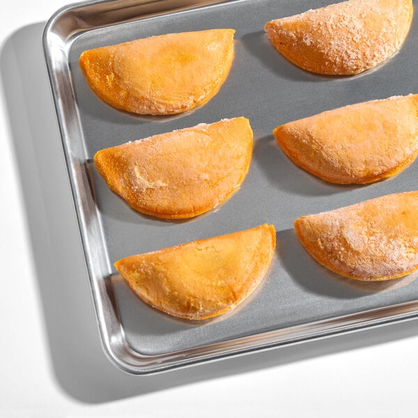 A tray of six frozen chicken and potato corn shell empanadas.