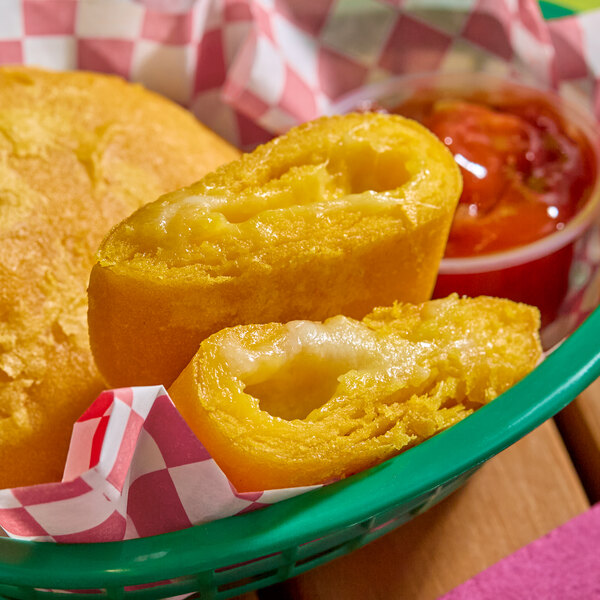 A mozzarella cheese-filled corn shell empanada cut in half, served in a green basket with a side of red dipping sauce.
