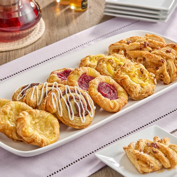 A rectangular white platter with an assortment of mini Danish pastries in various flavors and shapes.