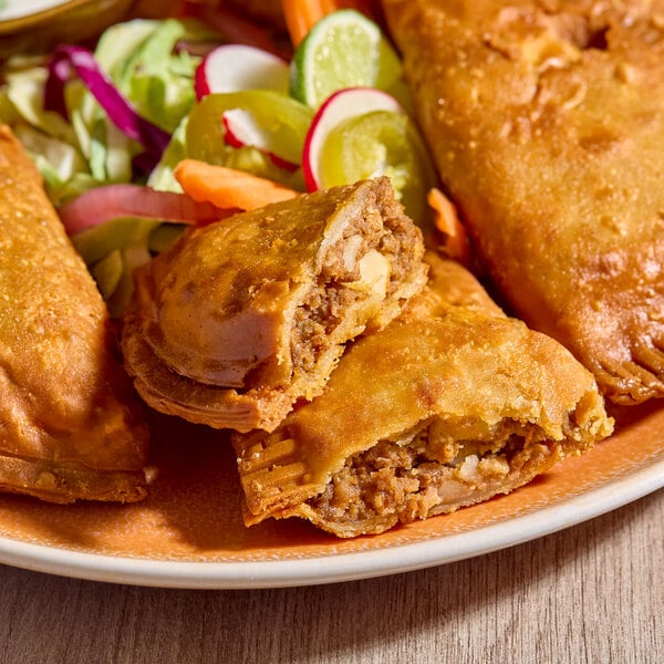 A plate of beef picadillo empanadas with a flour shell, served with a side of mixed vegetables.
