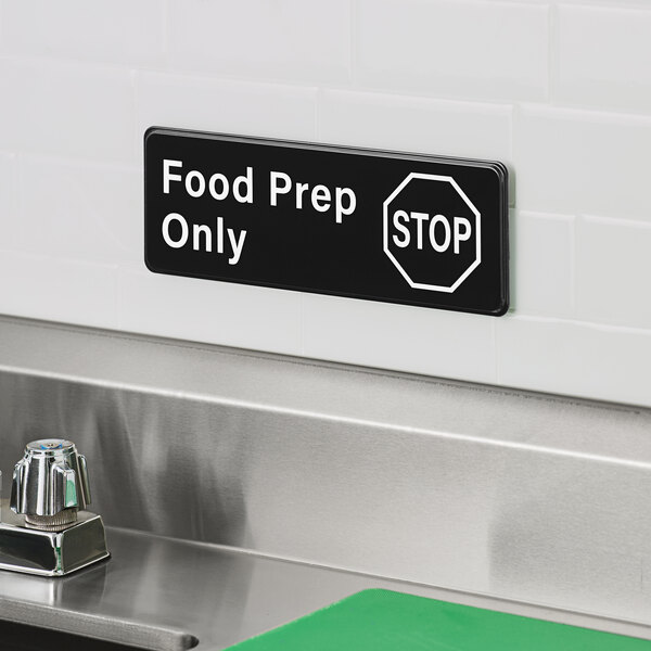 A rectangular black and white sign that reads 'Food Prep Only' with a stop symbol, mounted on a wall above a sink.