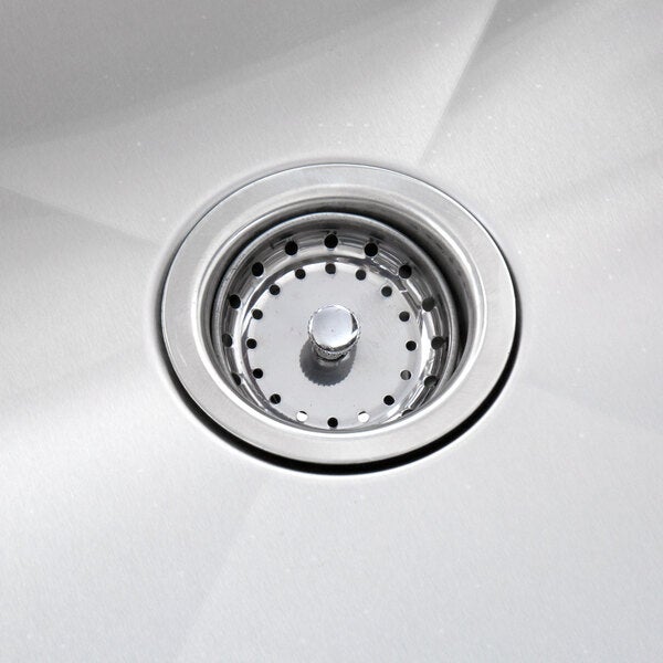 A stainless steel sink drain with a strainer basket in a commercial sink.