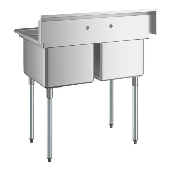 A stainless steel two-compartment sink with four metal legs and a high backsplash featuring two faucet holes.