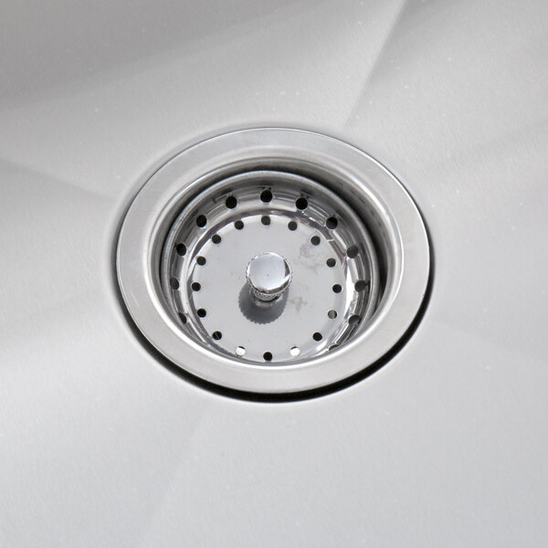 A stainless steel sink drain with a perforated strainer in a commercial sink.