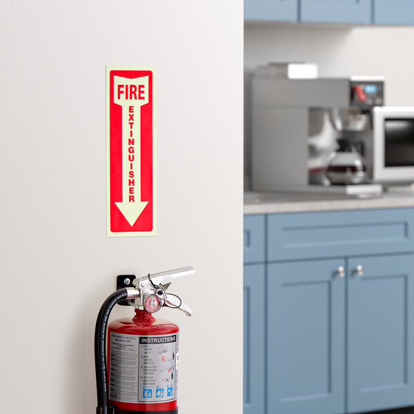 A red and white adhesive vinyl glow-in-the-dark safety label with a down arrow indicating the location of a fire extinguisher.