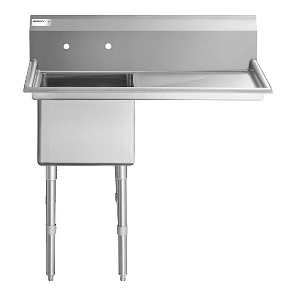 A stainless steel commercial sink with one deep basin, two faucet holes, and a right-side drainboard, supported by metal legs.