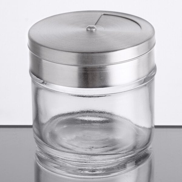 A small clear glass spice shaker with a stainless steel adjustable lid.