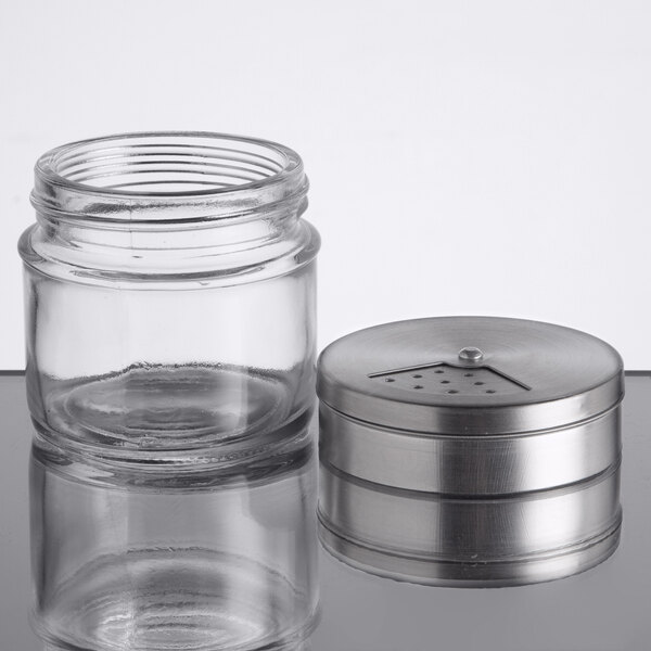 A small clear glass spice shaker with a removable stainless steel adjustable lid.