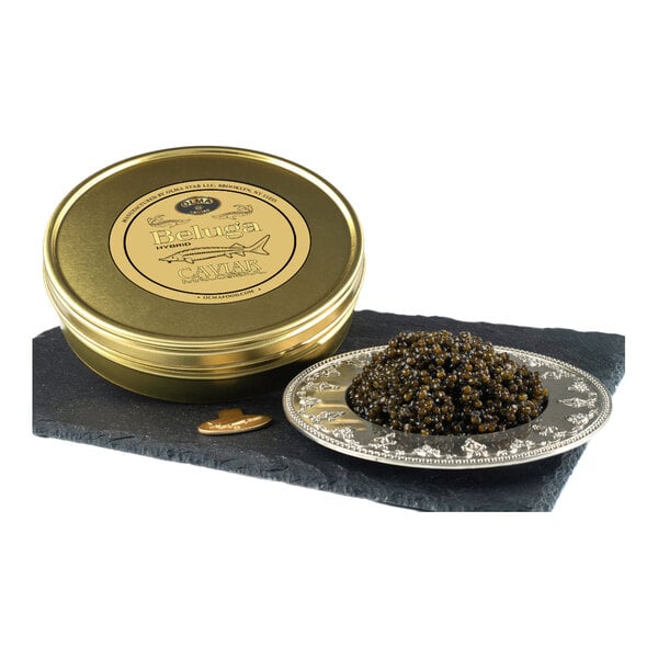 A tin of OLMA Beluga Hybrid Caviar alongside a serving of caviar on a decorative plate.