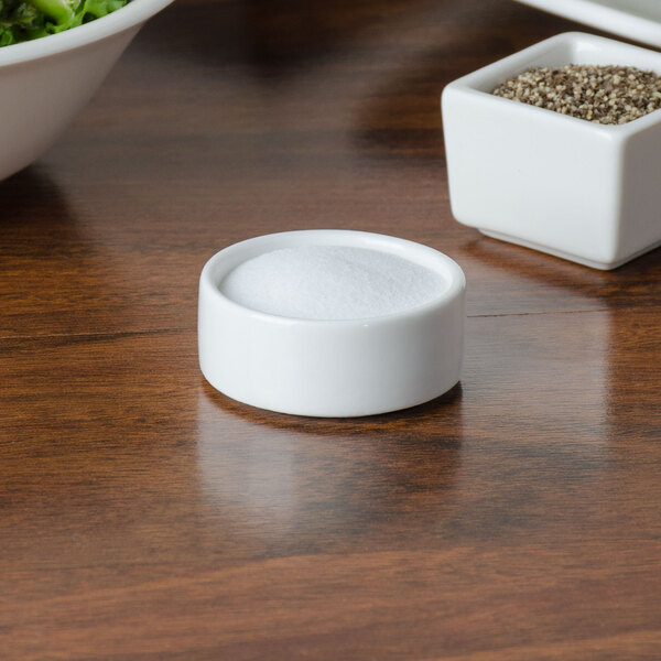 A small white round porcelain dish filled with salt.