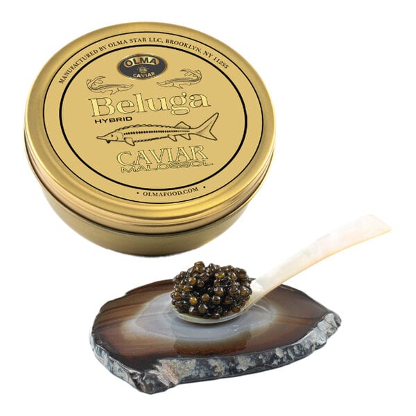 A tin of OLMA Beluga Hybrid Caviar with a spoonful of caviar resting on a stone serving dish.