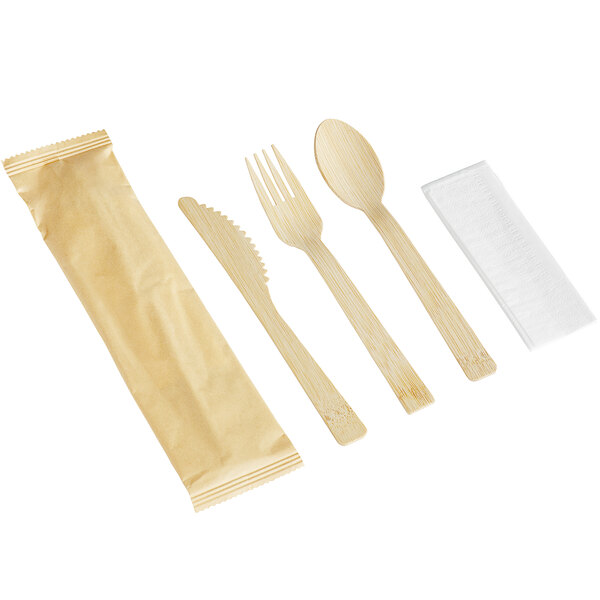 A compostable bamboo cutlery set with a knife, fork, spoon, napkin, and a paper wrapper.