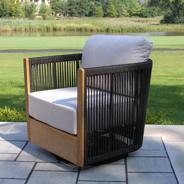 An outdoor swivel chair featuring black rope sides, teak wood frame, and light gray Sunbrella cushions.