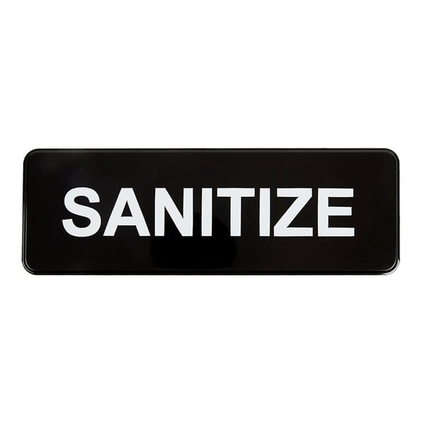 A rectangular black and white plastic sign with the word 'SANITIZE' in bold letters.