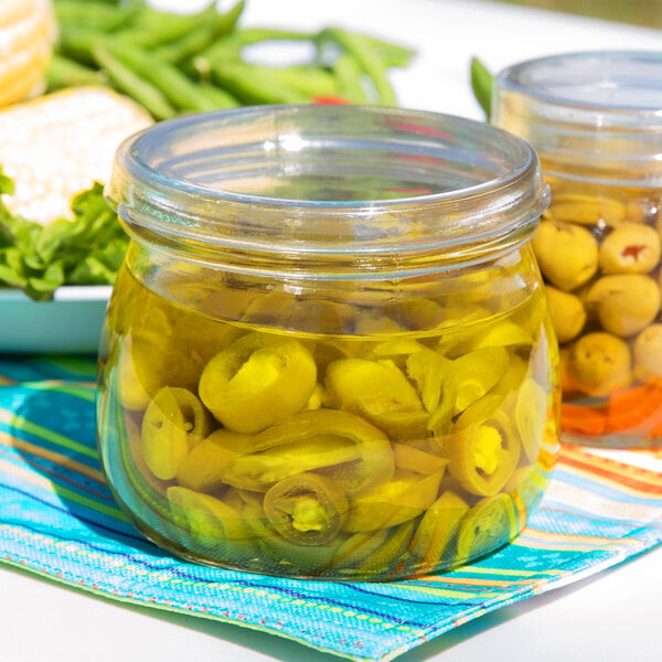 A clear glass mason jar filled with sliced green olives, used for condiments.