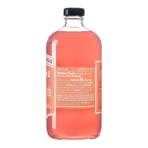 A clear glass bottle filled with pink Stirrings Paloma Mix and sealed with a black cap.