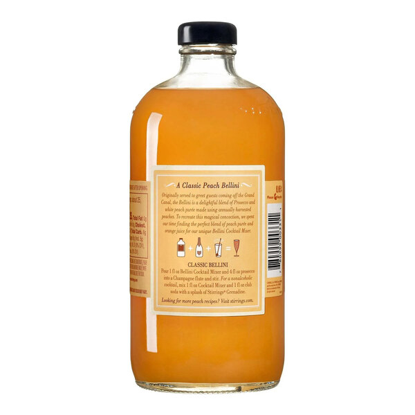 A 750 mL bottle of Stirrings Peach Bellini Mix with a black cap and a peach-colored liquid inside.