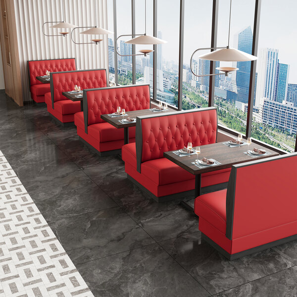 A bright red upholstered double booth with a button-tufted back and walnut finishes, designed for restaurant seating.