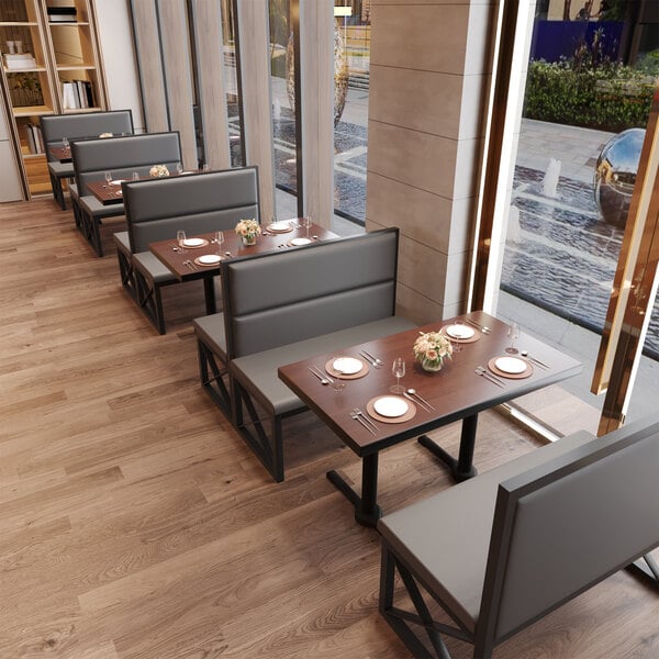 A black metal single booth with gunmetal vinyl upholstery and a wooden table, designed for restaurant seating.