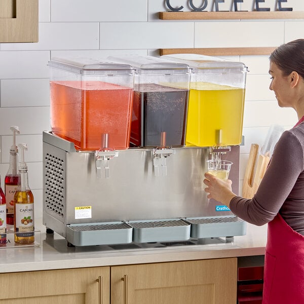 A triple-bowl refrigerated beverage dispenser with clear containers holding different colored drinks, designed for serving cold beverages.