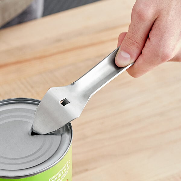 A metal bottle and can punch opener being used to puncture the lid of a can.