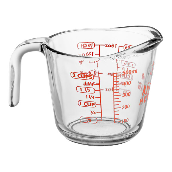 A clear glass measuring cup with red measurement markings and a handle.