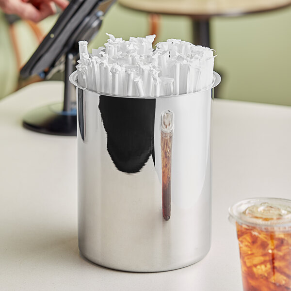 A stainless steel bain marie pot filled with wrapped straws on a countertop.