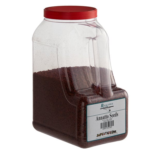 A large plastic container with a red lid filled with annatto seeds.