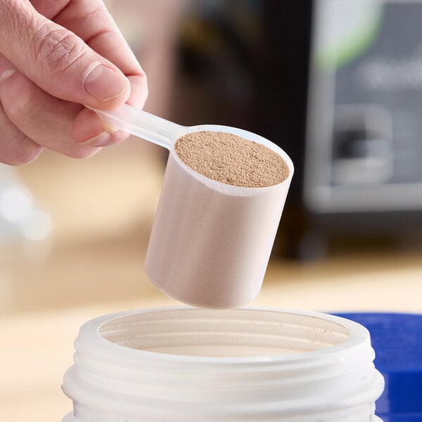 An 80 cc polypropylene scoop with a short handle being used to measure powder from a container.