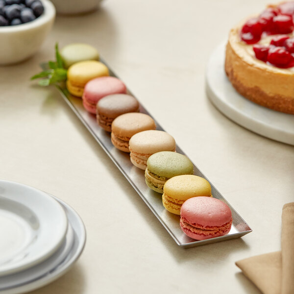 A rectangular stainless steel appetizer tray with an angled brim, shown holding assorted macarons.